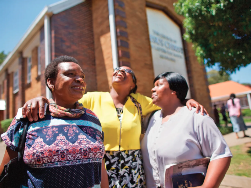 Women standing in front of a meetinghouse.