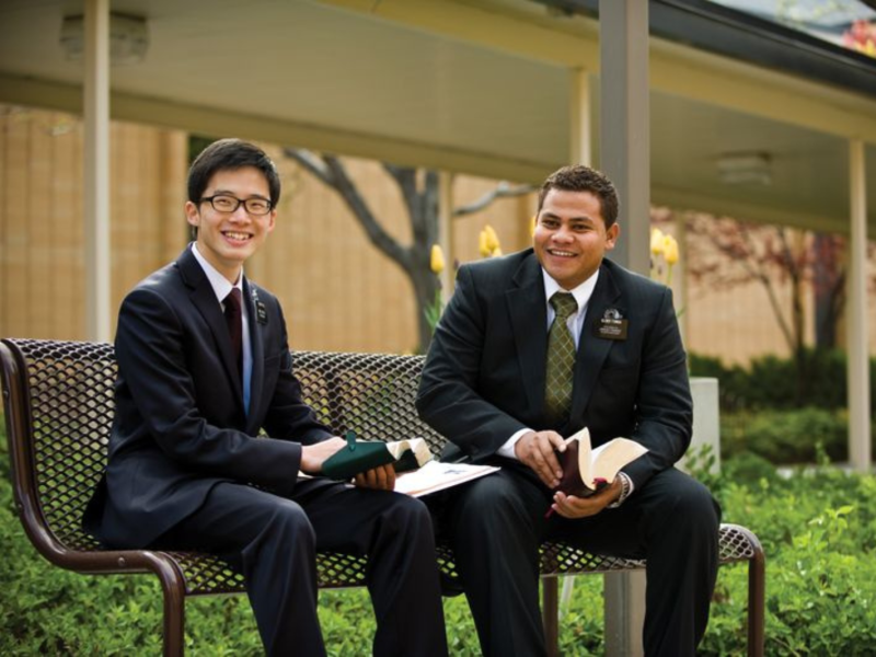 Two elders study scriptures on a bench at the Missionary Training Center.
