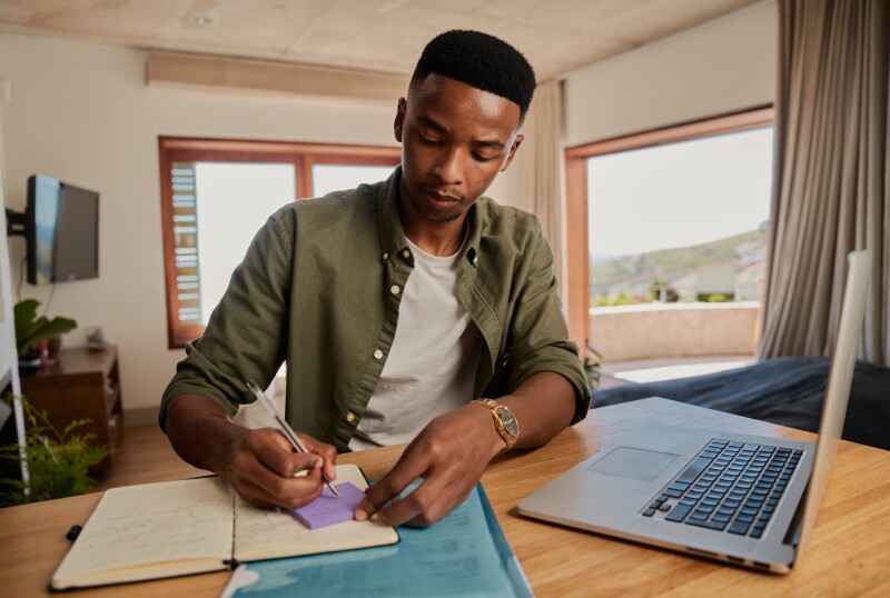 A young man writes on a sticky note.