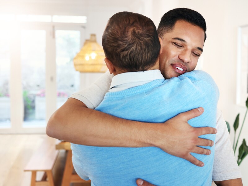 Love, care and father and son with a hug for a visit, bonding and quality time. Happy, affection and dad hugging a man with an embrace after reunited, missing or showing appreciation in a home