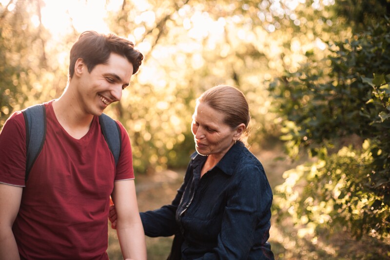 Happy mother and son laughing while standing in park during summer
