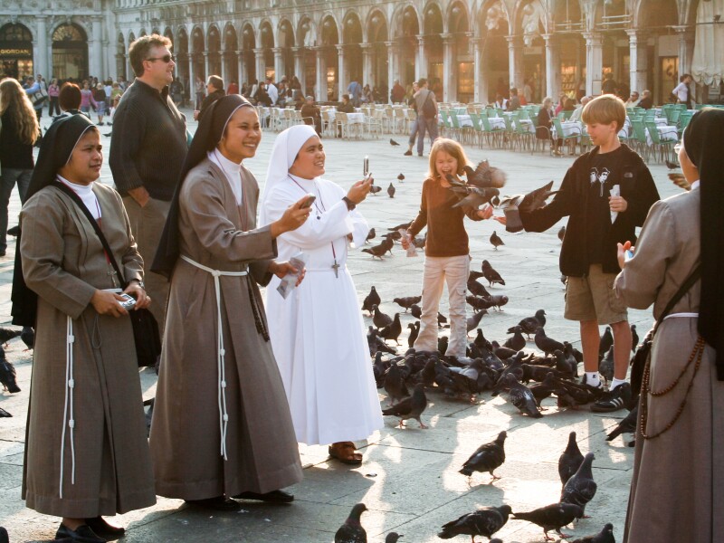 Nuns on San Marco square feed large flock of pigeons