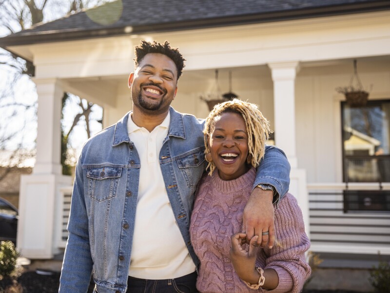 Portrait of husband and wife embracing in front of home