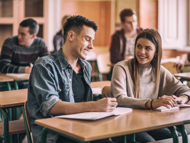 Happy high school friends talking in the classroom.