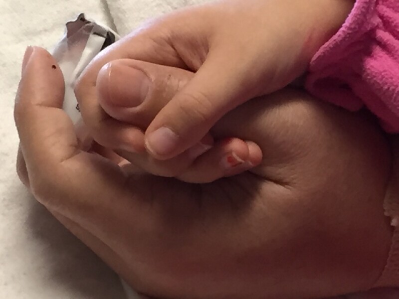 Lecia's daughter holding her husband's hand while he was in the hospital.