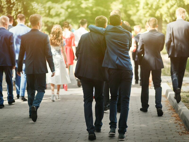 stylish confident man in suit having fun, group of people walking, reception at luxury wedding, rich graduation at school or university