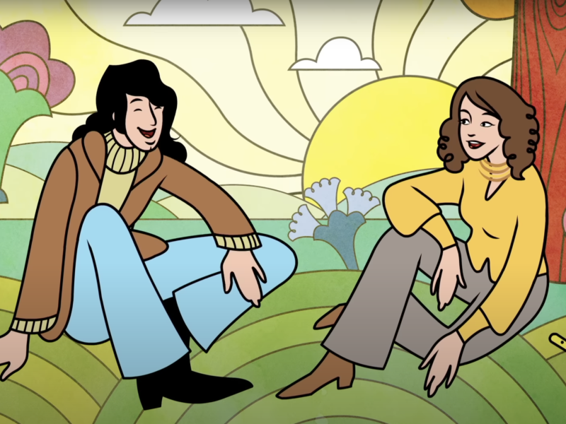 A young man and a young woman sitting on a hill talk and laugh together.