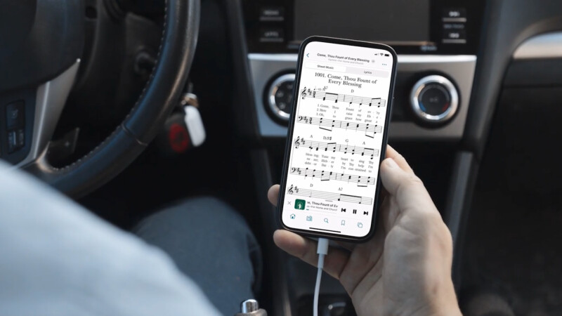 A smart phone shows digital sheet music for “Come, Thou Fount of Every Blessing.”