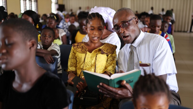 A congregation in a Latter-day Saint chapel sings from the hymnbook.