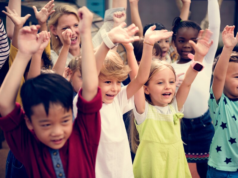 Primary aged children raise their hands.