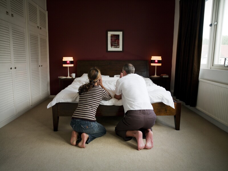 Mature couple kneeling by bed, praying, rear view