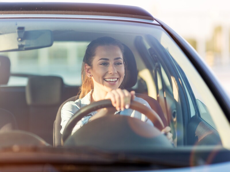 Happy woman driving a car and smiling