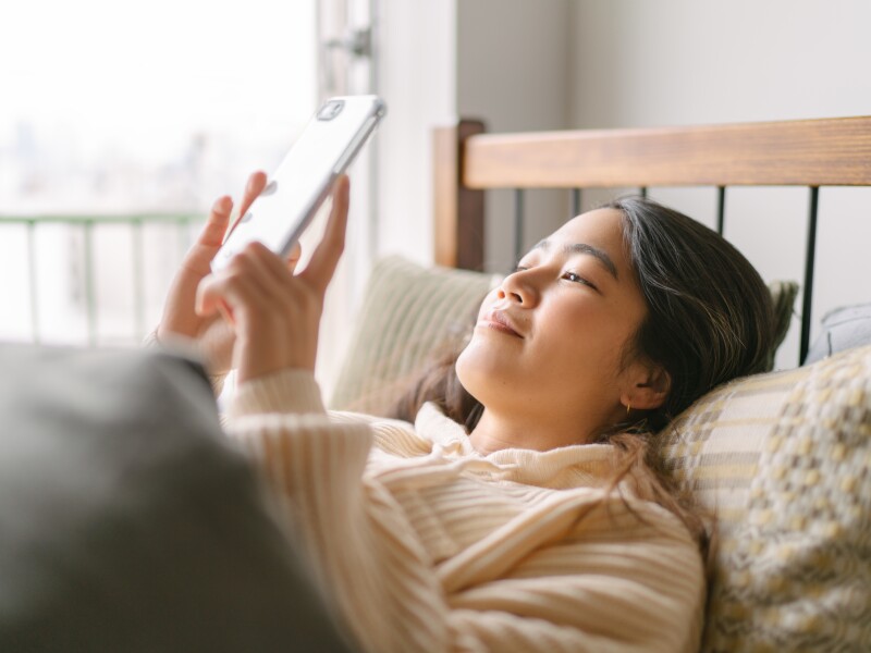 Young and beautiful woman using smart phone in bed in the morning
