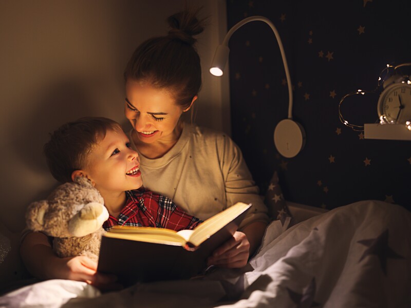 Cheerful mother and son cuddling and reading book