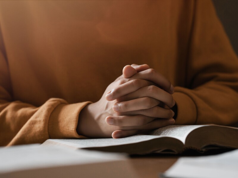 Hands folded over scriptures.