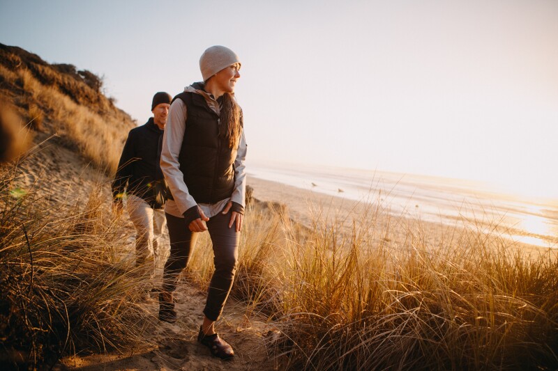 A couple walking near the a shoreline.