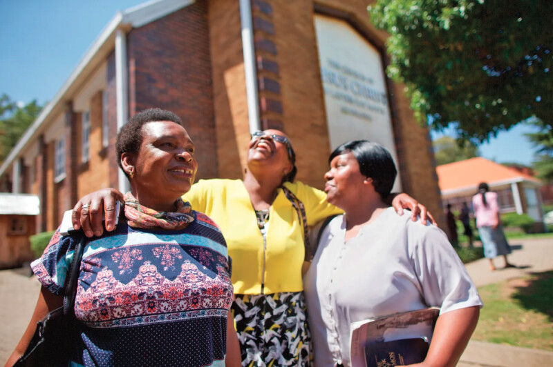 Women standing in front of a meetinghouse.