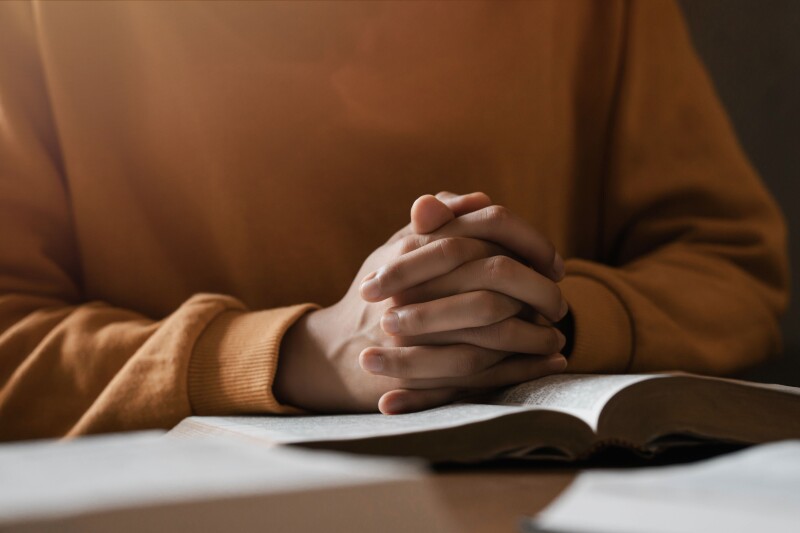 Hands folded over scriptures.