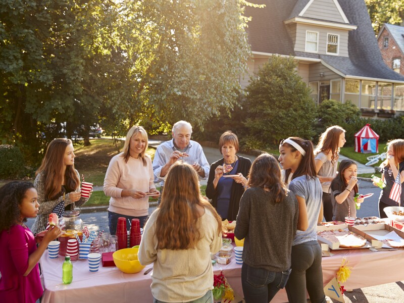 Neighbours talk and eat around a table at a block party