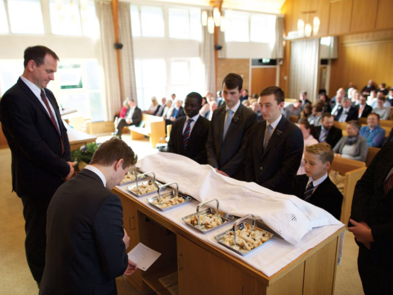 A young man blesses the bread as the sacrament is administered in a worship meeting in Norway.