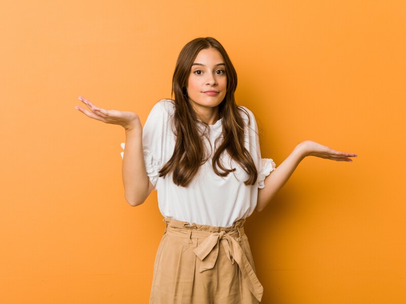 Young,Caucasian,Woman,Doubting,And,Shrugging,Shoulders,In,Questioning,Gesture.