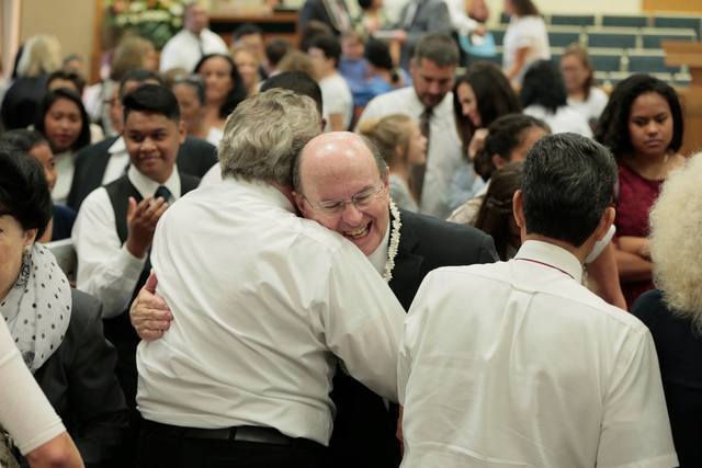 Image titleElder Cook with members of the Church. Image from Facebook.