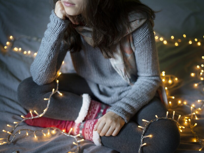 A young woman resting her head while sitting on a bed