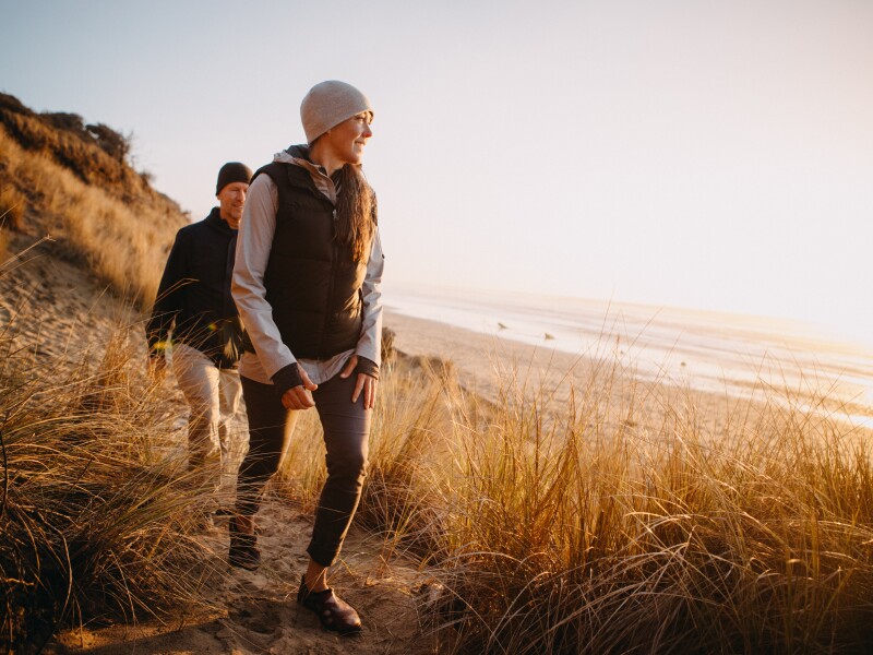 A couple walking near the a shoreline.