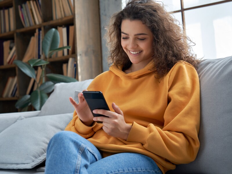 Happy,Millennial,Hispanic,Teen,Girl,Checking,Social,Media,Holding,Smartphone