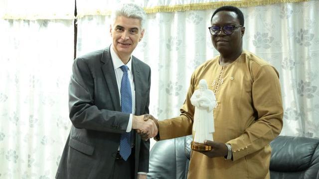 Presiding Bishop Gérald Caussé in a handshake with Orou Baro Mora, cabinet minister in the Ministry of Interior and Public Security in the Benin Republic, after the presentation of a gift from the Church.