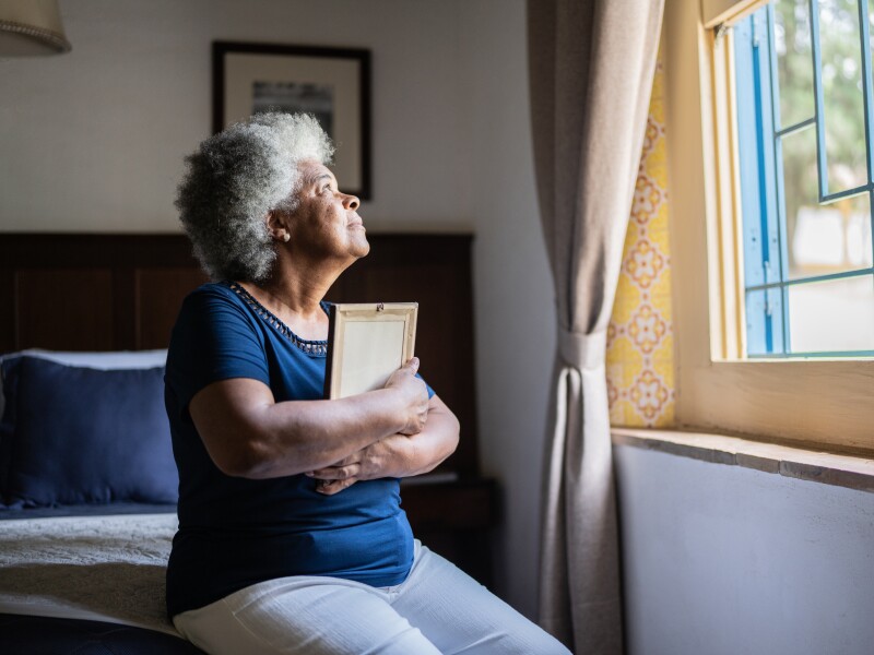 Senior woman holding a picture frame missing someone at home