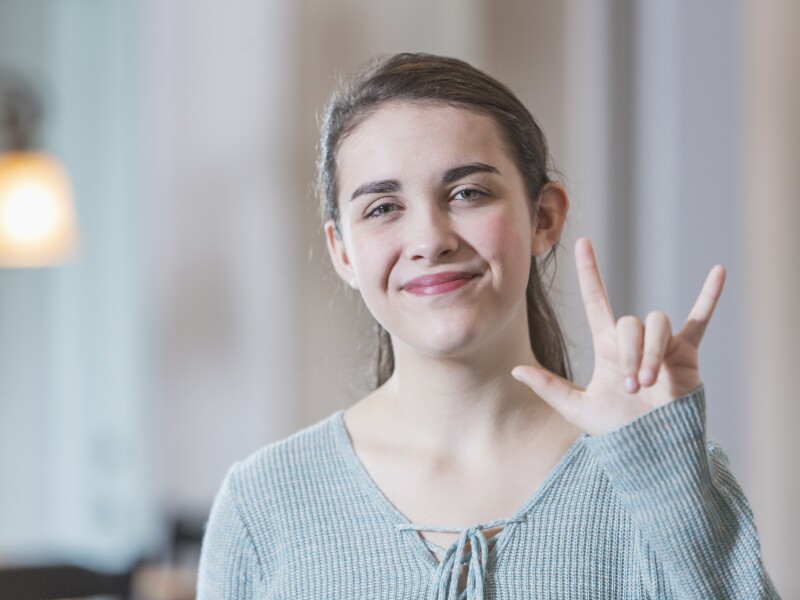 Teenage girl saying I Love You in sign language