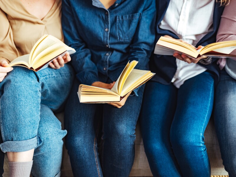 Diverse group of friends discussing a book in library.