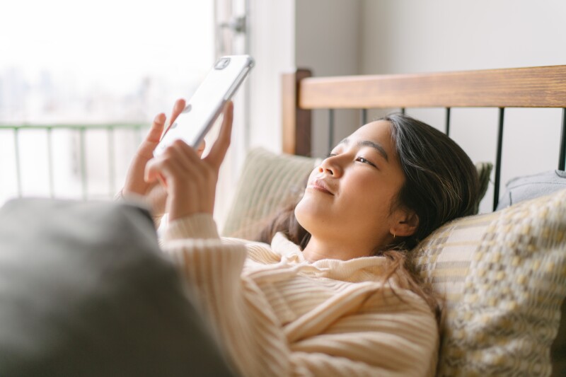 Young and beautiful woman using smart phone in bed in the morning