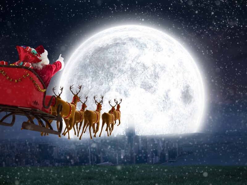 Santa,Claus,Riding,On,Sleigh,With,Gift,Box,Against,Bright