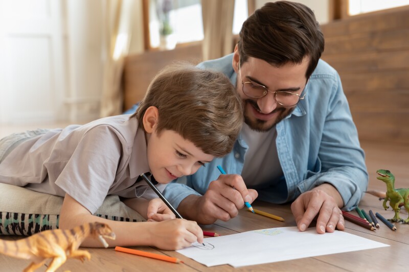 A father draws with his son. 