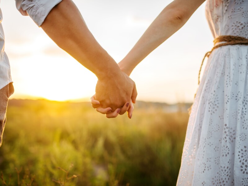 Couple,Hold,Hands,In,Green,Field,On,Sunset