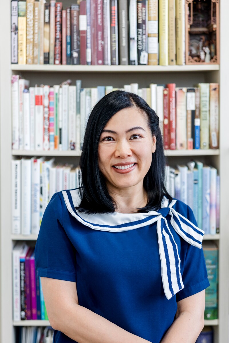 A woman smiles in front of a bookshelf