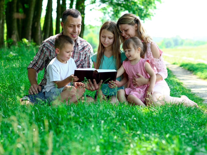 A young family studies the bible together.