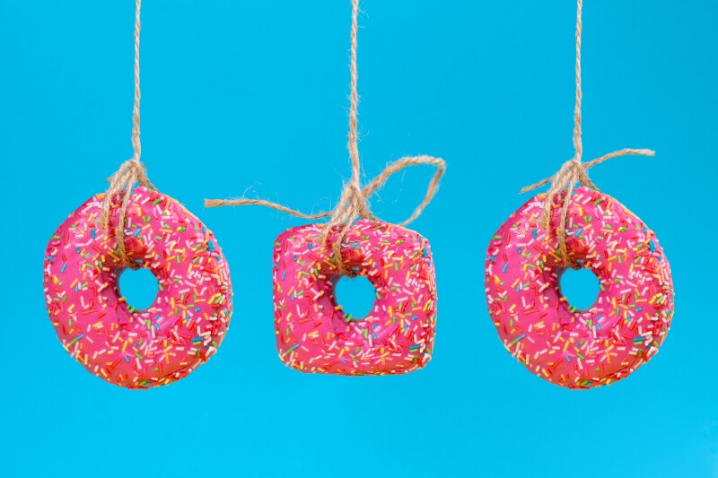 Three,Doughnuts,Of,Different,Shapes,With,Pink,Frosting,,Suspended,On