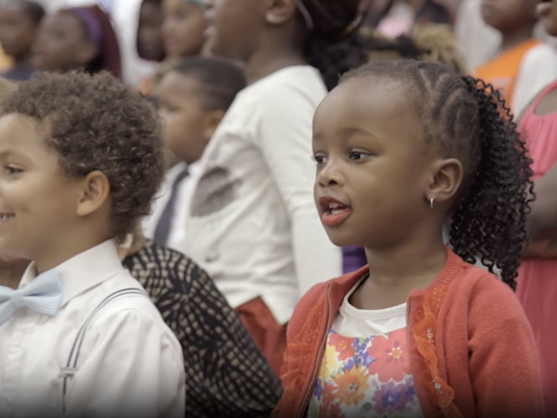 Two young children sing in a Primary music program.