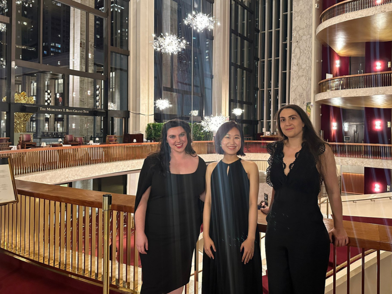 Three women stand in the lobby of the Metropolitan Opera.