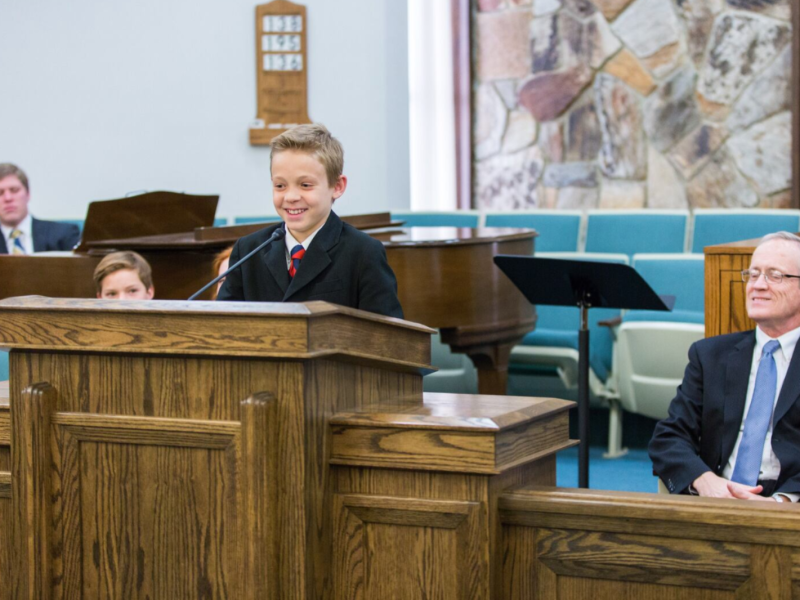 A boy gives a talk in a Latter-day Saint meetinghouse.