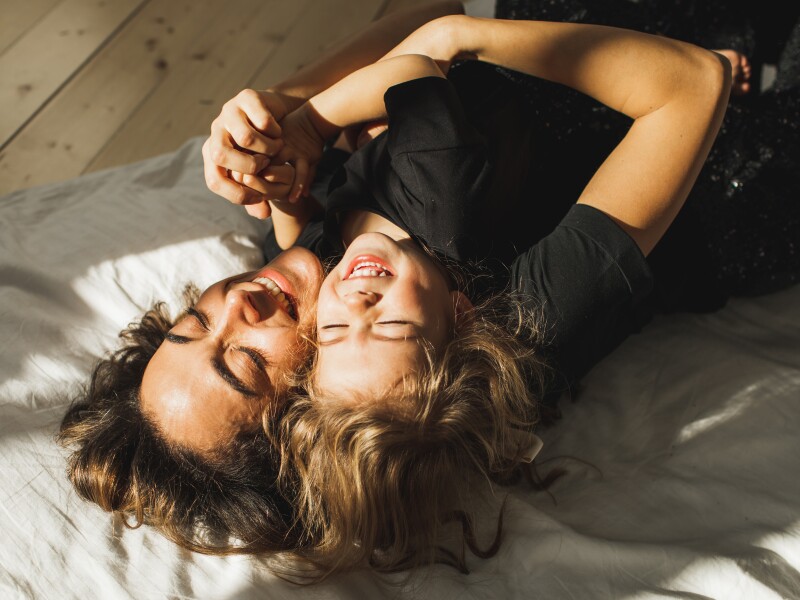 Beautiful mother and daughter having fun in bed.