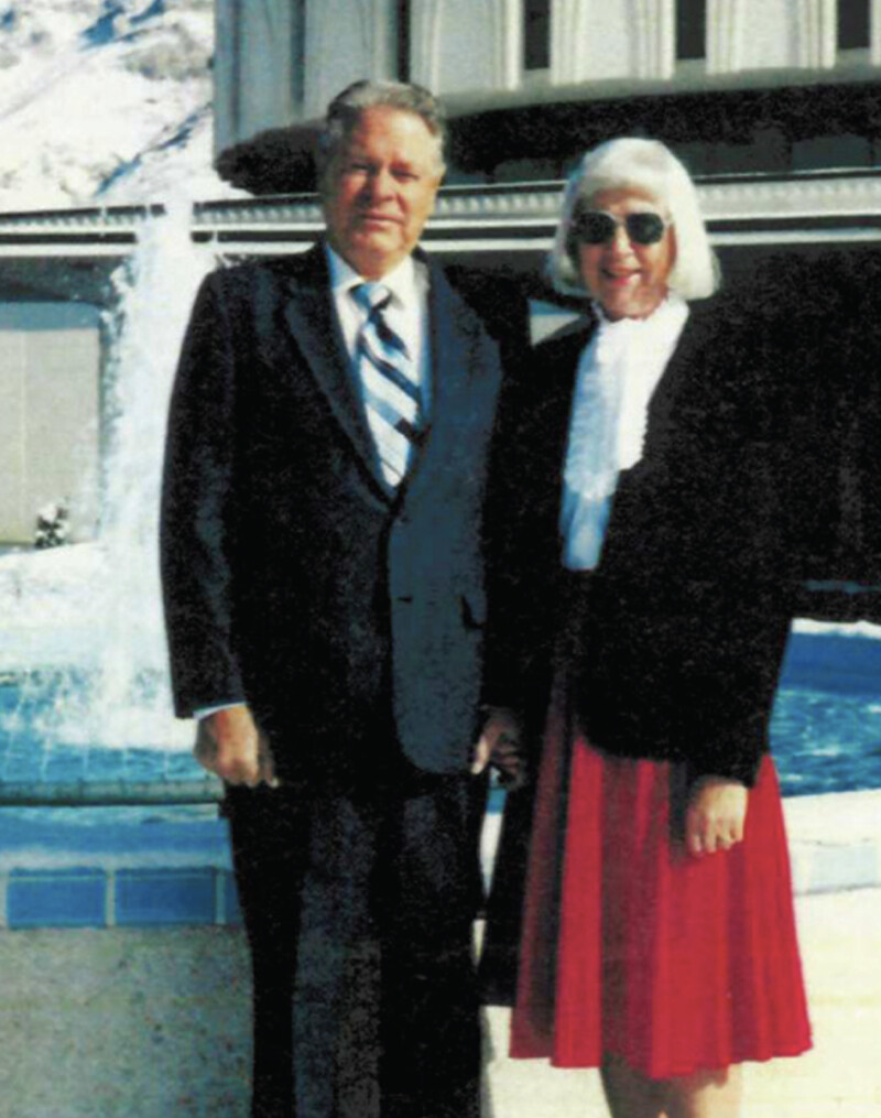 A man and woman smile next to a fountain in front of the Provo Utah Temple.