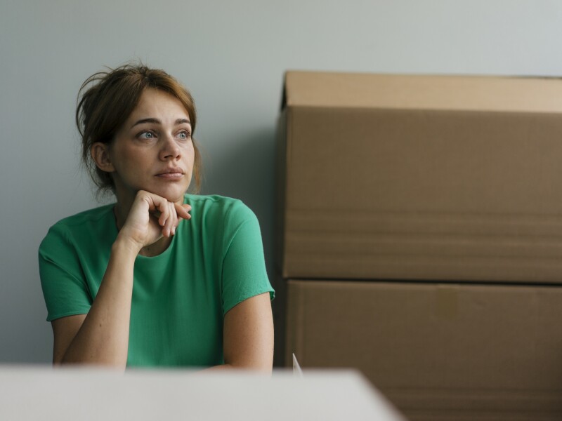 Thoughtful woman next to cardboard boxes in office