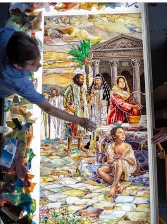 Tom Holdman assembles a stained glass piece over a light table.