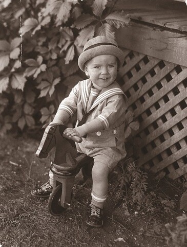 Russell M. Nelson as a young child sitting on a rocking horse outside.