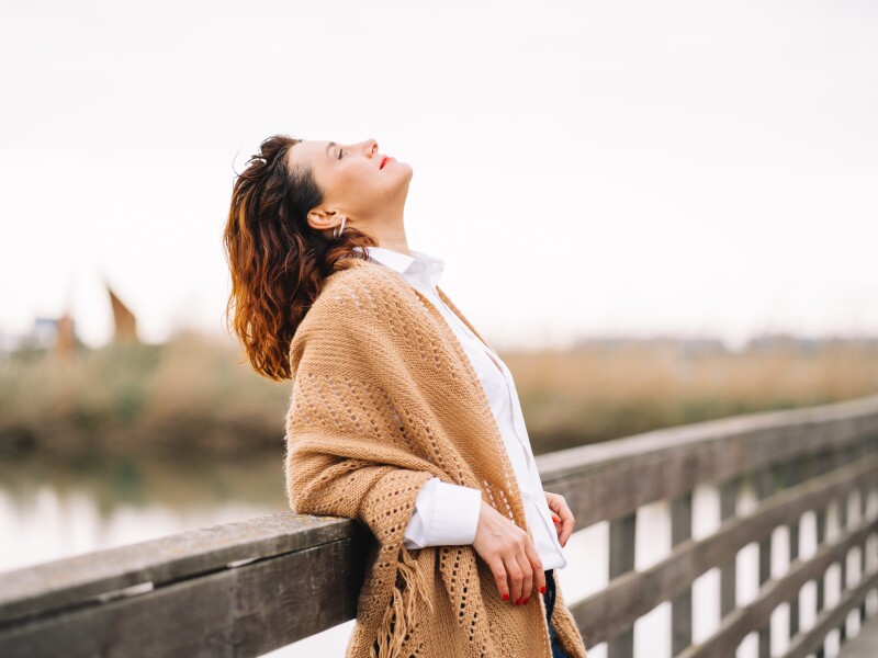 Mature woman walk alone in the part at autumn day and breathe with fresh cold air