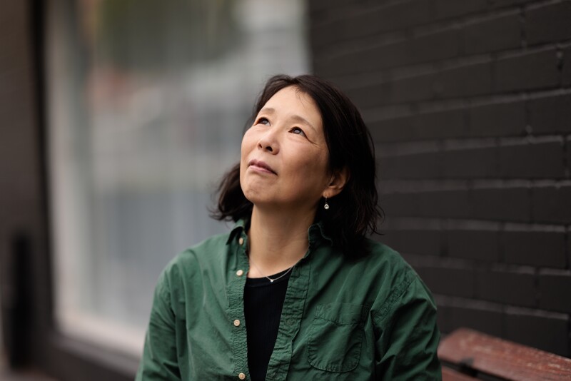 Asian woman standing outside, looking up.